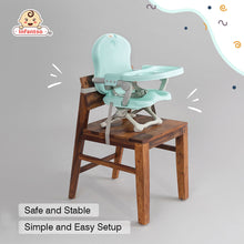 Green baby high chair on a dining stool 